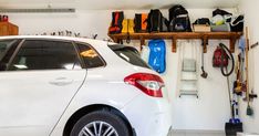 a white car parked in a garage next to a shelf filled with tools and equipment