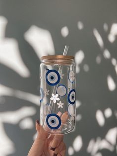 a hand holding up a glass with blue and white circles on it, in front of a wall