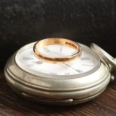 an old pocket watch with a wedding ring on it