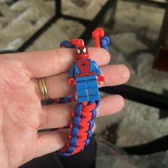 a hand holding a lego spider man bracelet