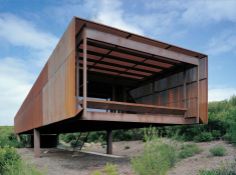 a large metal structure sitting on top of a lush green hillside under a blue sky