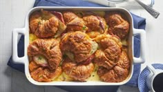 a casserole dish with ham and potatoes in it on a blue napkin next to a fork