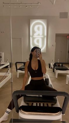 a woman taking a selfie while sitting on a chair in a room with mirrors