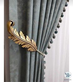 a curtain with a gold leaf on it and pom poms hanging from the side