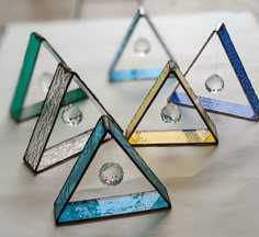 three glass pyramids sitting on top of a white table next to some crystal balls