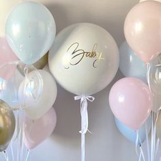 balloons and streamers with the word baby written on them in gold, white, and pink