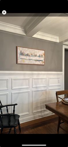 a dining room table and chairs in front of a wall with paneling on it