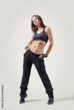 a woman in black pants and bra top posing with her hands on her hips