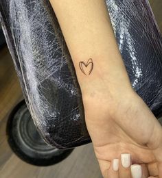 a small heart tattoo on the left inner forearm and wrist, with an arrow in the middle