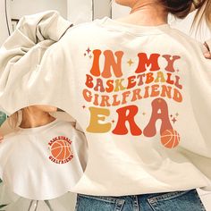 Trendy retro groovy in my basketball girlfriend era perfect for supporting boyfriend basketball players on game day! Great sports gift for high school sports, college sports, or professional sports.  Your order is supporting a sports mama's small business. Thank you so much!  ♡ How to order ♡ Please select a color (ash, sand, sport grey or white) and size (this is unisex sizing) Because our shirts are made to order, no refunds or exchanges. However, your satisfaction is top priority, so if you have any issues, please contact us immediately so we can make it right. Please note that color may differ slightly from how it appears on your screen due to varying monitor settings. Ideal for any situation, a unisex heavy blend crewneck sweatshirt is pure comfort. These garments are made from polyes Basketball Shirt Ideas For Boyfriend, Basketball Shirt Ideas For Girlfriend, Basketball Girlfriend Shirts, Girlfriend Basketball Shirts Ideas, Basketball Girlfriend Outfits, Basketball Girlfriend Shirts Ideas, Cute Basketball Girlfriend Shirts, Basketball Gf Shirts Design, Football Shirt Designs For Girlfriends