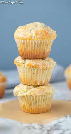 three lemon poppy seed muffins stacked on top of each other in front of the rest of the muffins