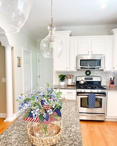 a kitchen with white cabinets and an american flag centerpiece on the island in front of the stove