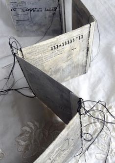 two wooden boxes sitting on top of a white cloth covered table with string attached to them