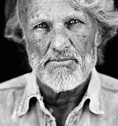 black and white photograph of an old man looking at the camera with wrinkles on his face