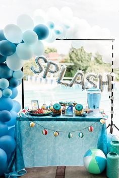 an outdoor pool party with balloons and streamers on the table, including a sign that says make a splash