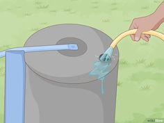 a hand is pumping water into a large barrel with a hose attached to it and dripping blue liquid from the top