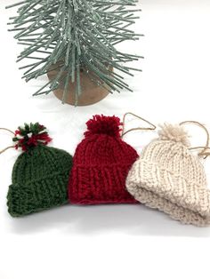 three knitted hats sitting next to a christmas tree