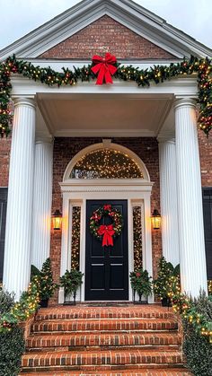 the front door is decorated for christmas with wreaths and garland on it's pillars