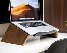 an open laptop computer sitting on top of a wooden stand