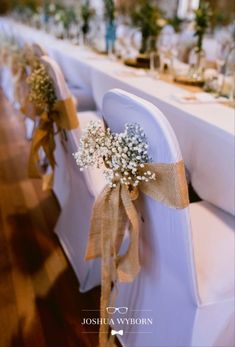 the chairs are decorated with baby's breath flowers and burlap ribbons for an elegant touch