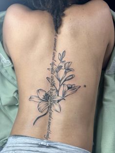 the back of a woman's lower back tattoo with flowers and words on it