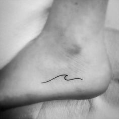 a black and white photo of a foot with a wave tattoo on the top of it