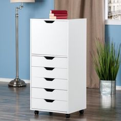 a white cabinet with five drawers and a lamp