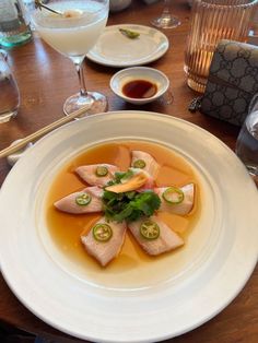 a white plate topped with food on top of a wooden table next to wine glasses