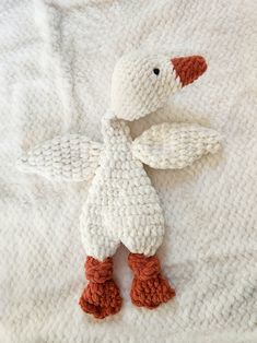 a knitted duck laying on top of a white blanket