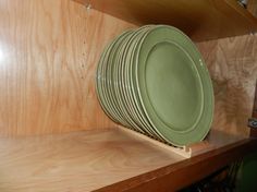 a stack of green plates sitting on top of a wooden shelf