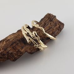 two gold rings sitting on top of a piece of driftwood next to each other