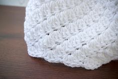 a white crocheted dishcloth sitting on top of a wooden table