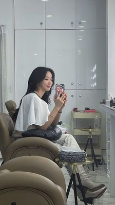 a woman sitting in a chair holding a cell phone