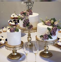 three tiered wedding cakes with purple flowers on top and two champagne flutes in front