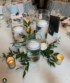 a table is set with candles, flowers and greenery for an elegant wedding reception