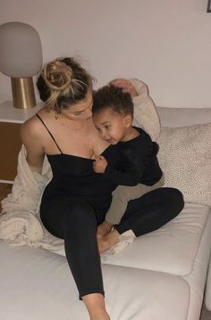 a woman sitting on top of a white couch holding a child