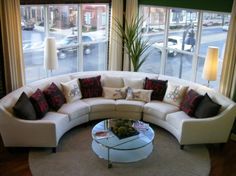 a living room filled with lots of furniture and large windows overlooking the city street outside