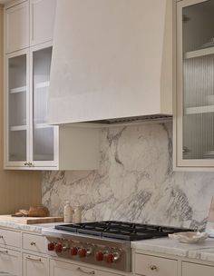 a stove top oven sitting inside of a kitchen next to white cabinets and counter tops