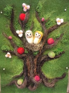 two owls are sitting in the middle of a tree with apples and grass around it