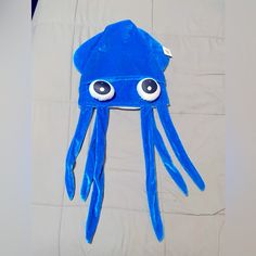 a blue hat with googly eyes on top of a white bed sheet that has been made to look like an octopus