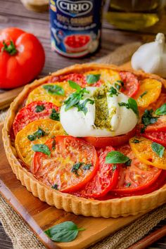 a tomato tart with basil and mozzarella on top sitting on a cutting board