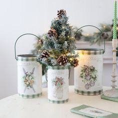 three tin canisters decorated with pine cones and christmas decorations are sitting on a table