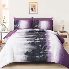 a bed with purple and white comforters in a room