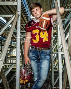 a young man wearing a football jersey and holding a helmet is posing for the camera