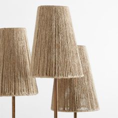 three lamps made out of rope and gold colored metal rods, each with a different shade