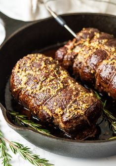 meatloaf in a skillet with rosemary sprinkled on the top and sides