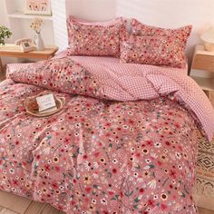 a bed with pink and red flowers on the comforter, pillows and pillow cases