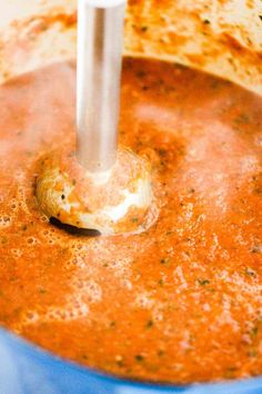 a blue pot filled with soup and a metal ladle sticking out of the top