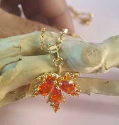 A beautiful and elegant design of the maple leaf in reddish orange zircon embedded in 18k gold plated copper material.  Necklace is also 18k gold plated copper. Hi quality craftsmanship.  Perfect gift for all occasions. Gold Plated Leaf-shaped Jewelry For Gifts, Orange Cubic Zirconia Jewelry As A Gift, Orange Cubic Zirconia Jewelry For Gift, Orange Cubic Zirconia Jewelry Gift, Maple Leaf Necklace, Reddish Orange, Copper Material, Leaf Necklace, Maple Leaf