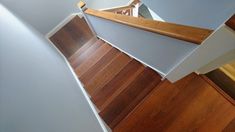 an overhead view of stairs and wood flooring in a house with white walls, hardwood floors and wooden handrails